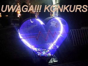 W ciemności widać podświetlony pojemnik na nakrętki w kształcie serca. Nad nim napis: &quot;Uwaga !!!! Konkurs&quot;.