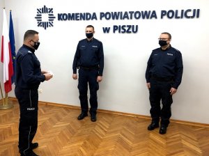 Po lewej stoi nadinsp. Tomasz Klimek, który składa podziękowania dla stojących przed nim po lewej asp. A. Trzonkowskiemu i po prawej asp. M. Rogowskiemu.