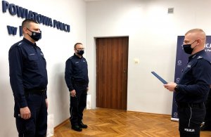 Po lewej widać asp. Adama Trzonkowskiego, obok asp. Mariusza Rogowskiego, a przed nimi stoi Komendant Powiatowy Policji  w Piszu trzymając w ręku podziękowania dla wyróżnionych policjantów.