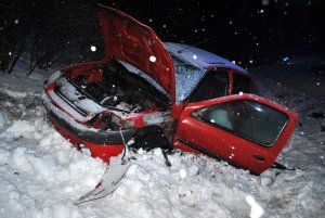 Samochód marki Renault koloru czerwonego na poboczu w śniegu. Ma uszkodzony przód.