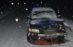 Na zaśnieżonej drodze, na prawym pasie drogi, stoi przodem niebieski Volkswagen z uszkodzonym przodem.