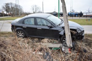 Widoczny jest y bokiem stojący samochód marki Alfa Romeo, nad którym pochylony jest słup energetyczny.