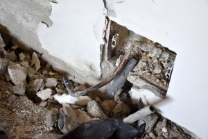Widoczna dziura w ścianie i powyrywane częściowo rury.