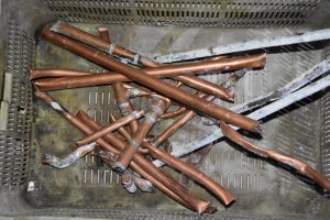 W koszu leżą miedziane rurki, które zostały wyrwane ze ściany i podłogi.