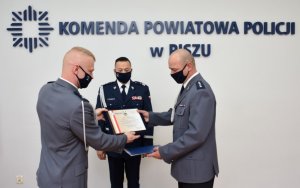 Komendant Powiatowy (stojący po lewej) wręcza nadkom. G. Kobeczce (stojącemu po prawej) pamiątkowy ryngraf.