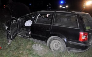 Nocą widać rozbity samochód uczestniczący w zdarzeniu drogowym.
