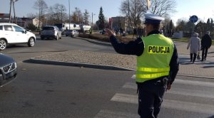 Umundurowany policjant kierujący ruchem w pobliżu cmentarza w Piszu.