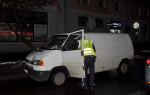 W ciemności policjant stojący przy białym busie uczestniczącym w potrąceniu pieszej na przejściu dla pieszych w Piszu.