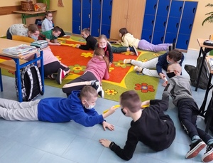 Uczniowie na podłodze w trackie zabawy ruchowej.