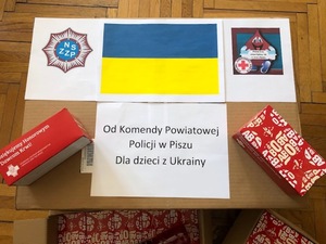 Karton z czekoladami. Na nim naklejona kartka z flagą ukraińską i napisem, że to dla dzieci z Ukrainy.