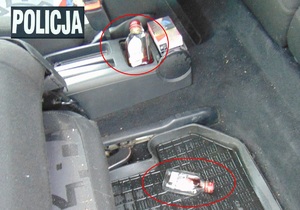 Wnętrze samochodu. Na siedzeniu oraz na podłodze leża małe puste butelki po alkoholu.