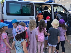 Dzieci wchodzą do policyjnego busa, by go zobaczyć w środku.