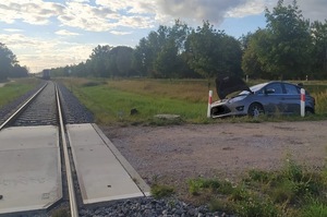 Po prawej w rowie przy przejeździe kolejowym stoi samochód z rozbitym przodem.