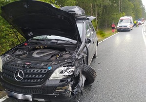 Na drodze stoi mercedes z otwartą przednią klapą. Samochód jest uszkodzony.