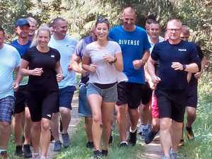 Grupa ludzi w sportowych strojach biegnąca po lesie.