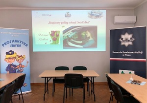 Sala konferencyjna. Slajd z napisem &quot;Bezpieczny poślizg z okazji Dnia Kobiet&quot;.