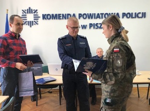 Sala konferencyjna. Policjant wręcza kobiecie dyplom.