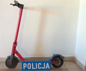 Oparta o ścianę czerwona hulajnoga. Na dole napis POLICJA