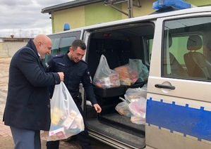 Policjant i mężczyzna pakują paczki do radiowozu