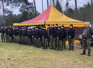 Na polanie w lesie stoi młodzież klasy mundurowej.