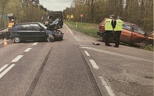 Droga i dwa rozbite samochody osobowe. Przy jednym z nich stoją dwaj policjanci.