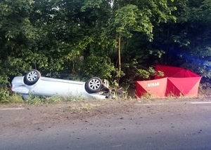 W przydrożnym rowie po lewej srebrny samochód na dachu, a po prawej czerwony parawan z napisem straż.