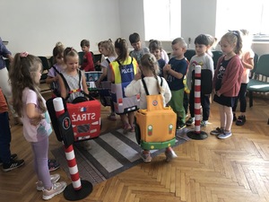 Sala odpraw w Komendzie Powiatowej Policji w Piszu. dzieci bawią się w miasteczku ruchu drogowego.