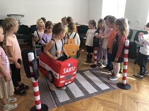 Sala odpraw w Komendzie Powiatowej Policji w Piszu. dzieci bawią się w miasteczku ruchu drogowego.