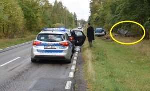 Miejsce wypadku. Na drodze radiowóz, a po prawej w rowie samochód na dachu.